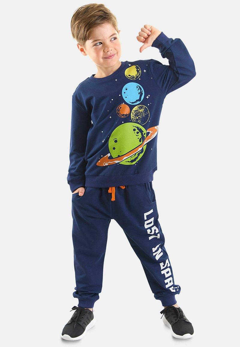 Sudadera azul marino con un gráfico temático del espacio, combinada con pantalones jogger a juego que presentan el texto "PERDIDO EN EL ESPACIO" en blanco. Cordón de color naranja brillante.