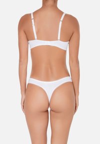 Ensemble de lingerie blanche avec un design lisse et minimal. Le soutien-gorge possède des bretelles réglables et une fermeture à crochets simple. Le string présente une coupe tout aussi épurée.
