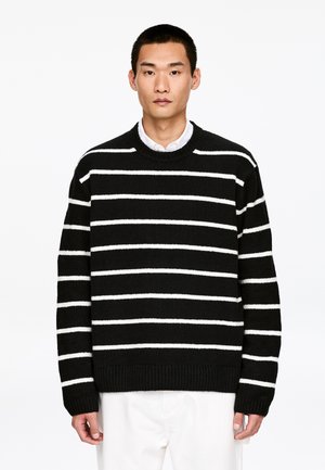 Schwarz-weiß gestreifter Strickpullover mit rundem Ausschnitt und gerippten Bündchen. Weiche Textur, lockere Passform und markante horizontale Streifen.