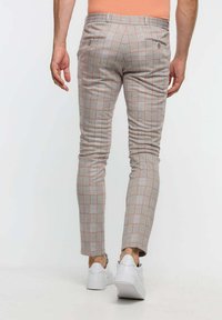 Lichtgrijze slim-fit broek met een subtiel ruitpatroon in het rood. Bevat twee achterzakken en een elastische tailleband voor comfort.