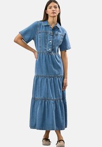 Denim maxi kleit lühikeste varrukatega, nööbid ees, kolmest kihist koosnev disain ja kontrastsete õmblustega; helesinine värv.