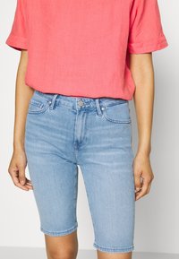 Bermuda shorts in denim azzurro chiaro con un design aderente, cinque tasche e orlo arrotolato. Abbinati a una maglietta corallo morbida.