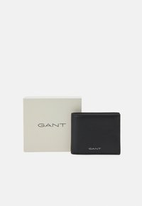 Black leather wallet with smooth texture, featuring stitched edges, a GANT logo on the front, and a white gift box.