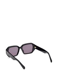 Ochelari de soare hexagonali negri cu lentile de culoare violet închis, ramă din acetat lucios și accente aurii pe brațe.