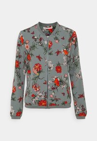 Zielona kurtka zapinana na zamek z nadrukiem czerwonych, różowych i białych kwiatów oraz ptaków, ze ściągaczem przy kołnierzu, mankietach i dolnym brzegu.