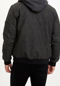 Sort bomberjakke med en glat tekstur, ribbede mansjetter og kant. Har en hætte og sidelommer. Casual design med en tætsiddende silhuet.