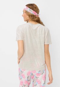 T-shirt grigio chiaro a maniche corte, con un leggero sheen. Abbinato a pantaloni con motivo rosa e blu. Capelli raccolti con una fascia abbinata.