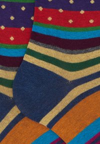 Calzini multicolori con motivi che includono pois, righe e larghezze variabili in tonalità di blu, rosso, verde, arancione e giallo.
