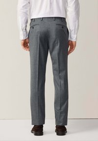 Grijze wollen broek met een gestructureerde afwerking, voorzien van twee achterzakken en een getailleerde pasvorm, gecombineerd met een wit overhemd.