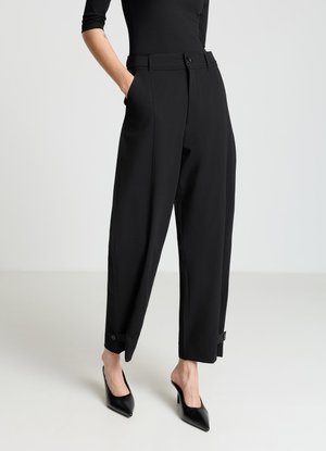 Pantalon noir taille haute à coupe ajustée, avec poches latérales et revers roulés. Tissu lisse avec une finition polie.