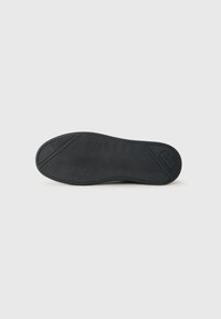 Rubber shoe sole, black, featuring herringbone tread pattern for grip, with raised accents enhancing traction and stability. Smooth surface.
