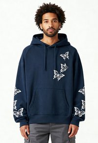 Sweat à capuche bleu marine en mélange de coton, avec une broderie blanche de papillons sur les manches et le devant, doté d'une poche kangourou et d'une capuche ajustable.