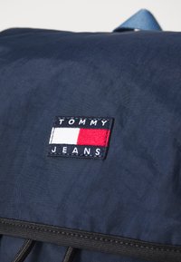 Námornícka látková batoh s obdĺžnikov�ým vyšívaným logom Tommy Jeans v námorníckej, bielej a červenej farbe, s prešitými detailmi a zipsom.