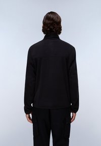 Black fleece pullover with a high collar, featuring a simple design, long sleeves, and a smooth texture, worn over dark cargo pants.