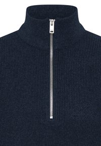 Pull en maille bleu marine foncé avec un col cheminée haut et une fermeture éclair argentée à l’avant partiellement fermée.