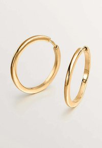 Pendientes de aro de oro con un acabado elegante y suave. Un pendiente es más pequeño; ambos presentan un diseño de bisagra sin costuras para facilitar su uso.