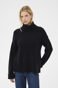Svart polotröja i ett mjukt, strukturerat tyg med vida ärmar. Styld med en avslappnad passform, tillsammans med blå denimjeans.