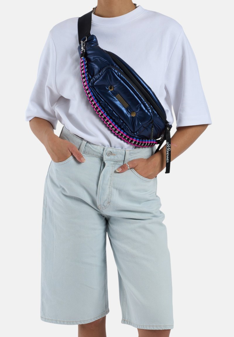 Marineblauwe puffer schoudertas met roze en zwarte gevlochten ritsdetails. Bevat een voorvak en een verstelbare zwarte strap. Gladde, glanzende verpakking.