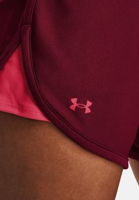 Burgunderfarbene Sportshorts mit einem pinken Innenfutter, ausgestattet mit einem kleinen pinken Under Armour-Logo am Saum, aus glattem Textilgewebe.