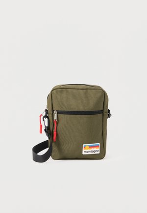 Sac bandoulière compact vert olive avec sangle noire, poche zippée à l'avant avec tirettes rouges, et patch "montagne" avec des rayures de coucher de soleil.