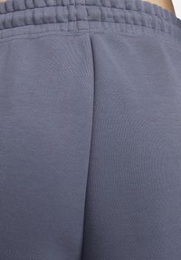 Donkerblauwe sweatpants met een textuurstof, elastische tailleband en schuine naadtoefeningen aan de achterkant voor een getailleerde uitstraling.