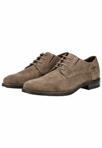 Zapatos de ante marrón con cordones, de textura suave, puntera alargada y suela oscura contrastante; presentan un sutil detalle de perforaciones.