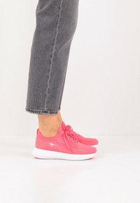 Ροζ αθλητικά παπούτσια από δίχτυ με λευκές σόλες, διαθέτουν στρογγυλή μύτη, επενδεδυμένο γιακά και σύστημα κορδονιών. Φοριούνται με γκρι cropped τζιν.