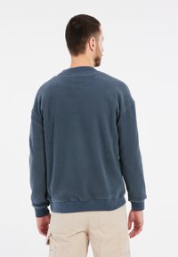 Felpa blu scuro realizzata in tessuto morbido, con polsini e orlo a coste, colletto a giro e vestibilità comoda. Adatta per un abbigliamento informale.