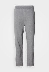Pantalones de chándal grises elaborados con un tejido suave, que cuentan con una cinturilla elástica, piernas ajustadas y un logo cerca de la zona del bolsillo.