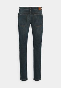 Mörkblå denimjeans med en tight design, fem fickor och en läderlapp vid midjan. Sömdetaljer längs fickorna.