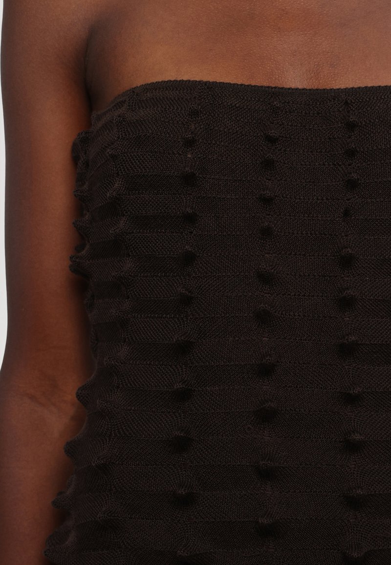 Top senza spalline marrone scuro con un design a coste testurizzato che presenta accenti di pallini in rilievo su tutto il tessuto. Realizzato in materiale a maglia.