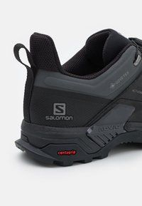 Chaussure de randonnée noire en Gore-Tex, avec surfaces texturées et lisses, logo Salomon, semelle extérieure Contagrip pour une adhérence optimale, et accents réfléchissants.