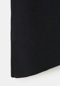 Gros plan sur un tissu en maille côtelée noire montrant des lignes verticales texturées et un bord d'ourlet légèrement incurvé.