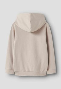 Sweat à capuche beige avec manches longues, poignets et ceinture côtelés, vu de dos sur un fond gris clair uni.