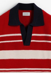 Polo de punto rojo con cuello azul marino y rayas horizontales blancas, etiquetado como Scalpers tamaño grande.