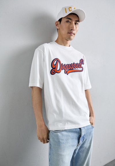 Witte katoenen t-shirt met een rood en blauw geborduurd "Dsquared²" logo. Gecombineerd met lichtblauwe spijkerbroek.