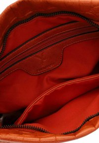 Interior de bolsa de piel naranja con estampado de cocodrilo, con dos compartimentos, que incluye un bolsillo con cremallera y forro de tela roja suave.