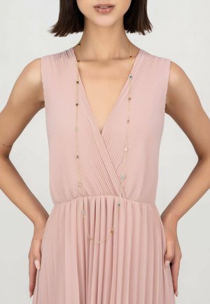 Long gold necklace with colorful beads draped over a pleated blush pink dress featuring a deep V-neck and gathered waist.