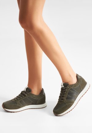 Olive green athletic shoes with mesh panels, textured accents, and a white sole. Features laces and a logo near the heel.