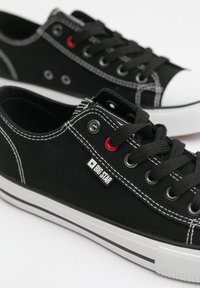 Sneaker in tela nera con suole e punte bianche in gomma, cuciture bianche a contrasto e occhielli rossi. Presenta un'etichetta "BIG STAR".