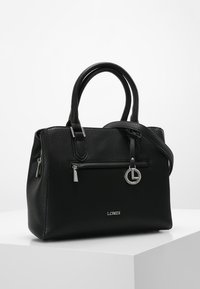 Sac à main en cuir noir texturé avec double poignée, une bandoulière amovible, des garnitures en argent, des poches zippées et un charme logo à l'avant.