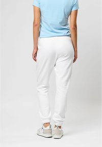 Hvide sweatpants med elastiske manchetter, parret med en lysblå t-shirt. Stoffet ser blødt ud med en afslappet pasform. Sneakers med et let design.