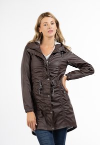Brun vandafvisende jakke med et figursyet design, snoreliv, knaplukninger, hætte og samlinger langs fronten og ærmerne.