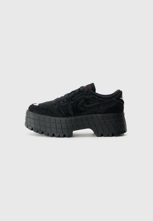 Czarny sneaker na platformie z grubą, fakturowaną podeszwą, puszystym materiałem wierzchnim, sznurowanym fasonem i subtelnym logo swoosh z boku.