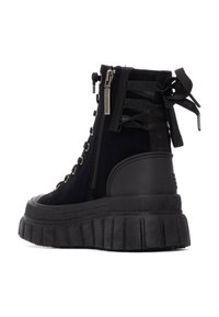 Botas negras hasta el tobillo con parte superior de ante, cierre de cordones en la parte delantera, cremallera y suela de goma gruesa con detalles acanalados y acentuaciones de cinta.