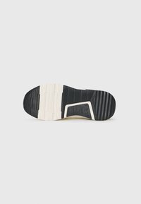 Suola di sneaker nera e crema caratterizzata da un motivo di gomma testurizzata, con una leggera curvatura e un design segmentato per trazione e supporto.