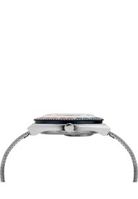 Montre en acier inoxydable avec un boîtier carré, une lunette noire et des accents rouges. Elle dispose d'un bracelet en maille métallique et d'un cadran en verre transparent.