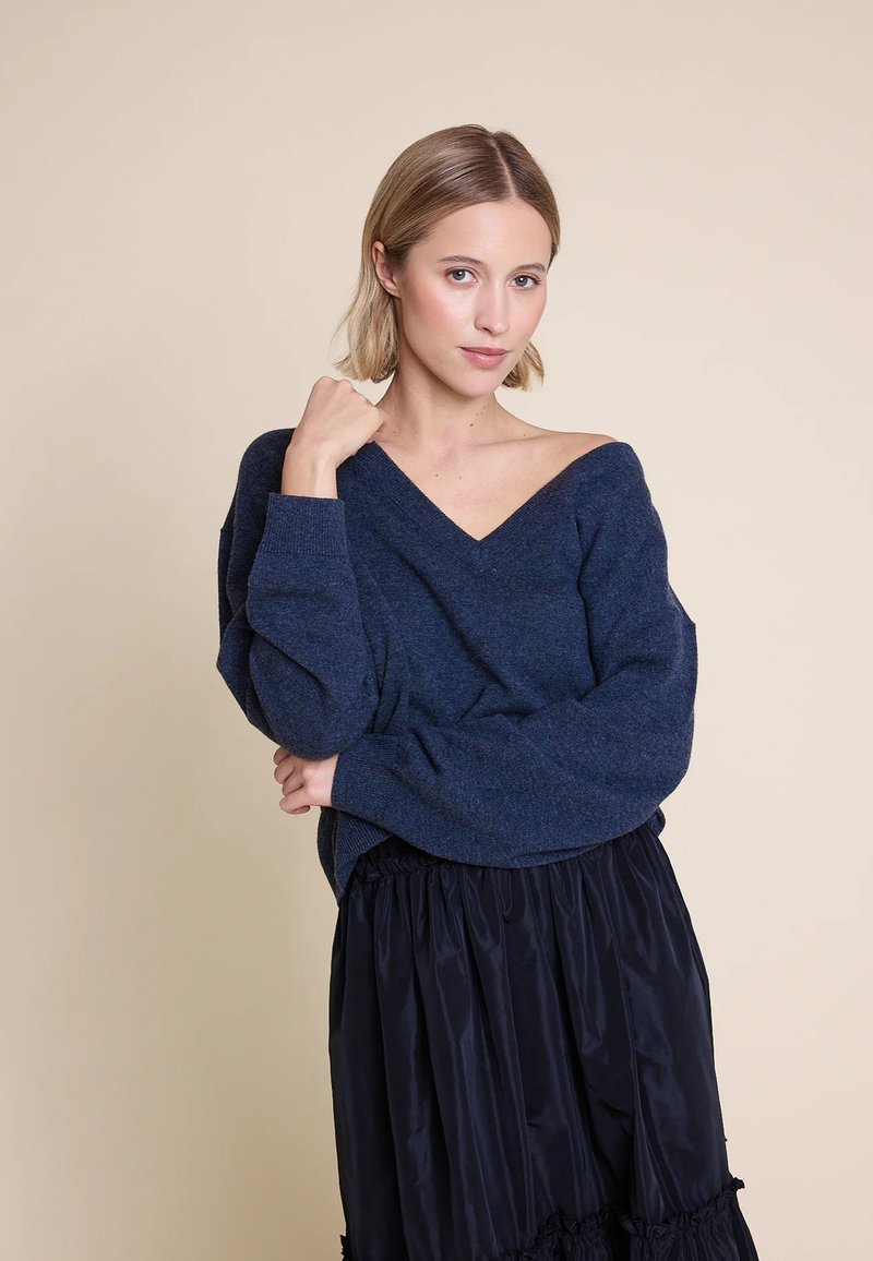 Marineblå, overdimensjonert v-hals genser med lange ermer. Laget av teksturert stoff, kombinert med en svart, volang midi-skjørt.