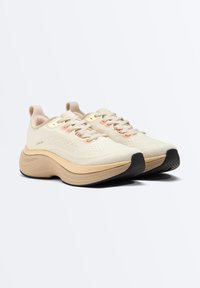 Paire de chaussures de course beiges et marron clair avec semelles épaisses, lacets et semelle extérieure noire texturée sur fond blanc.