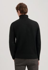 Schwarzer Strickpullover mit hohem Rippkragen, langen Ärmeln und einem gerippten Saum. Weiche Textur, keine sichtbaren Muster oder Beschläge.
